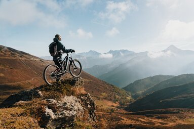 Mountainbiker mit Bike am Felsen mit Blick hinunter vom Brenner Grenzkamm | © TVB Wipptal | Johannes Bitter