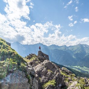 Wanderer auf einem Felsen unterhalb des Nösslachjochs in Steinach mit Blick ins Gschnitztal hinunter | © TVB Wipptal - Helena Beermeister