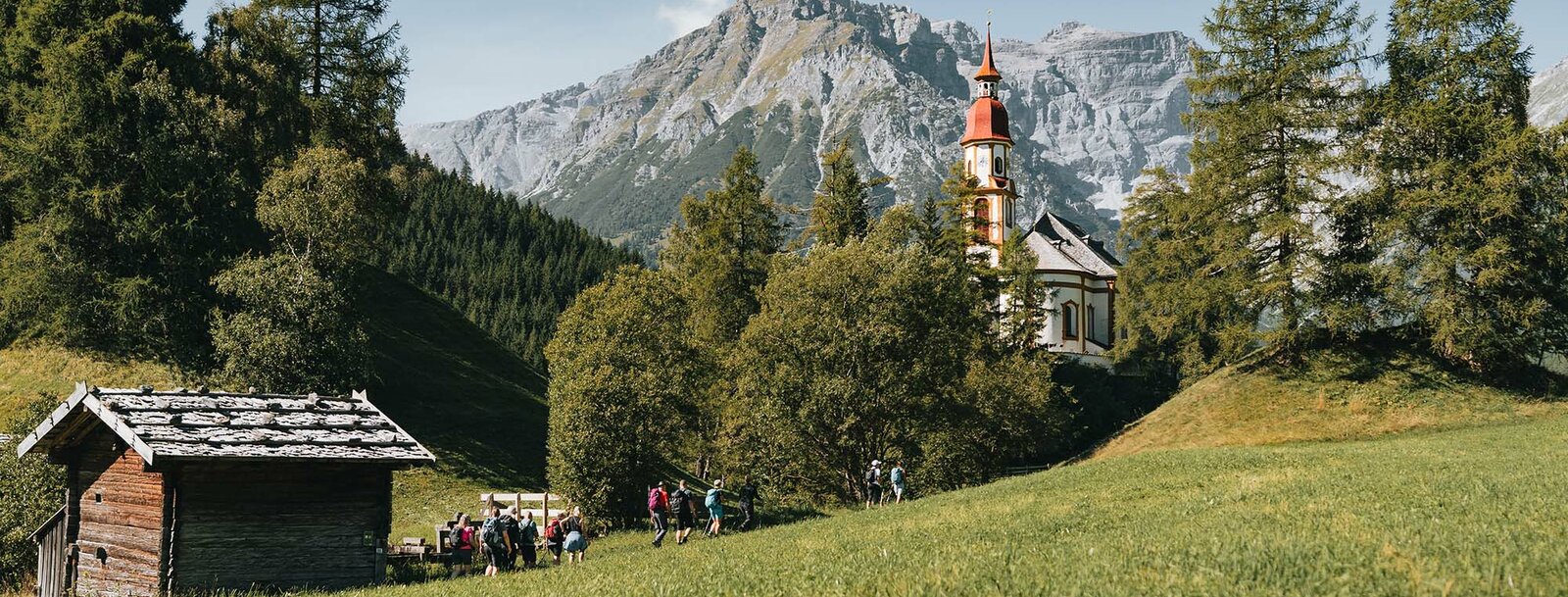Eine Gruppe wandert an der Kirche in Obernberg vorbei | © TVB Wipptal | Johannes Bitter