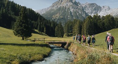Eine Wandergruppe geht entlang eines kleinen Baches in Obernberg | © TVB Wipptal | Johannes Bitter