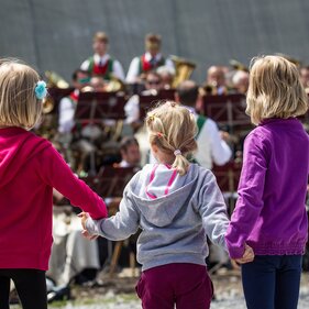 Mädchen halten Hände bei einem Fest mit Musikkapelle | © Tirol Werbung